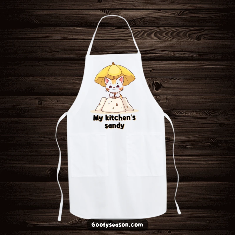 Funny apron showing a curious cat holding a sun umbrella by a sandcastle, ready for beach-themed cooking.