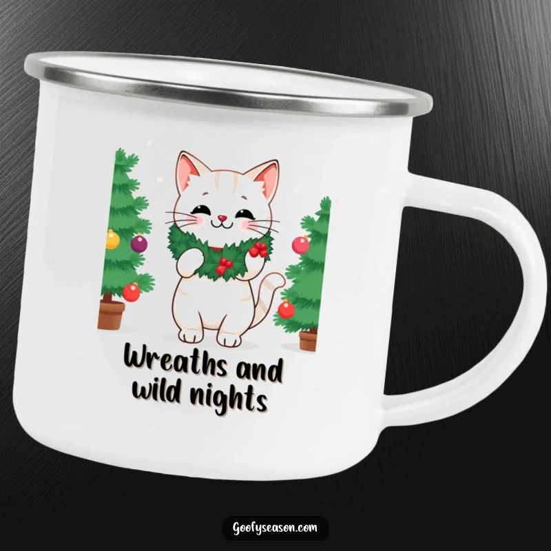 Funny enamel camping mug with a cheerful cat wearing a festive wreath, decorating a Christmas tree in a rustic setting.