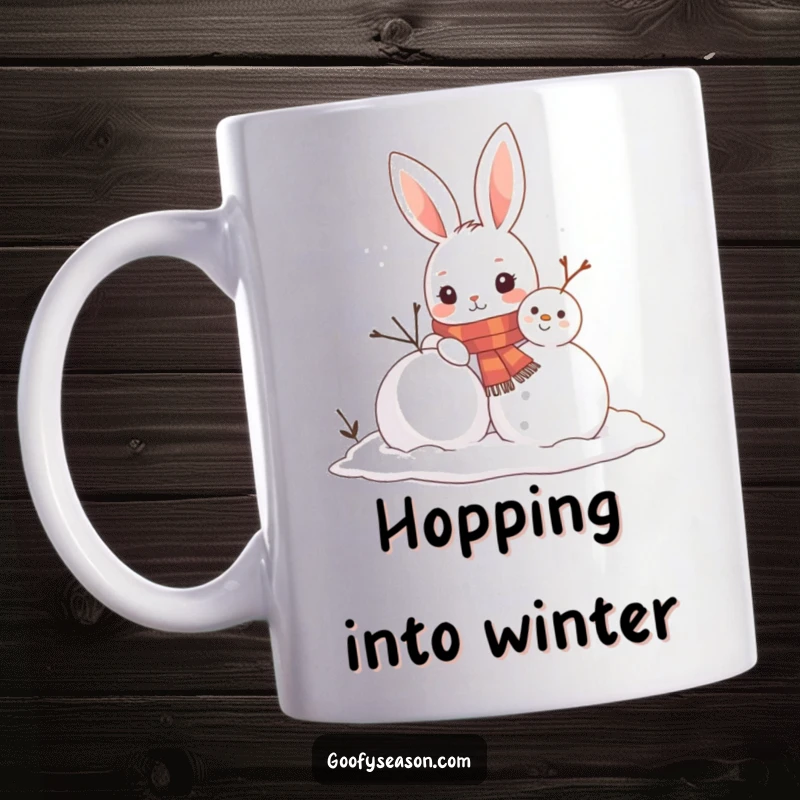 Funny mug featuring a curious bunny wearing a scarf, happily building a snowman with carrot nose and twig arms, creating winter cheer.