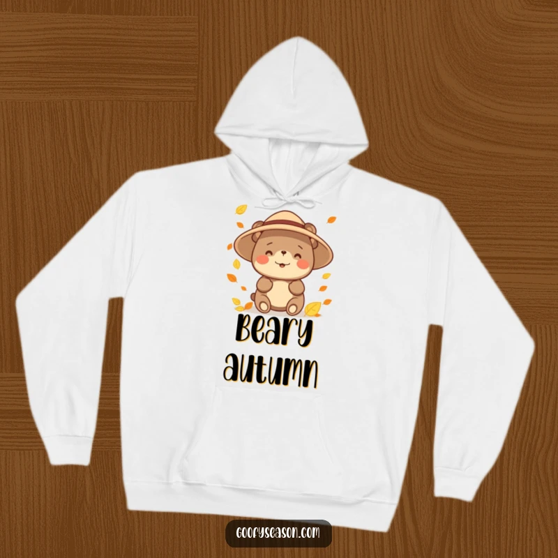Funny happy bear character wearing a sun hat, catching falling leaves on a cozy hoodie, ideal for autumn comfort.