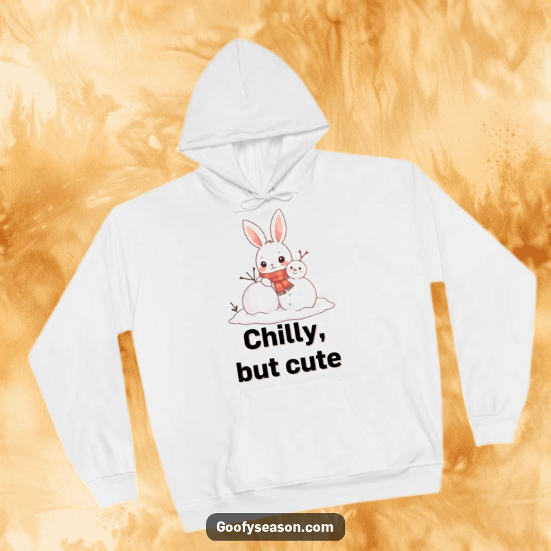 Funny hoodie featuring a curious bunny character wearing a scarf, busy building a snowman, perfect for staying warm and cheerful.