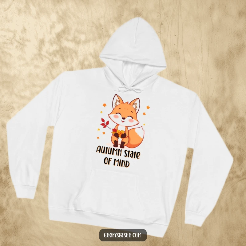 Funny, warm hoodie featuring a cheerful fox character holding colorful autumn leaves, perfect for fall enthusiasts.