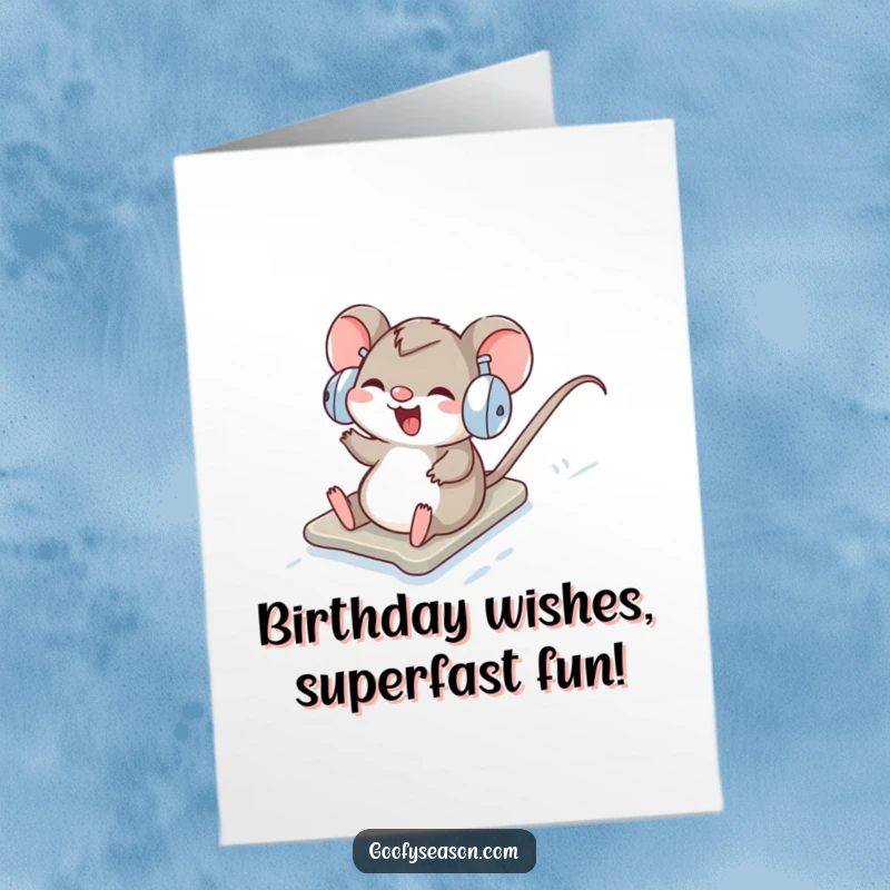 Funny Free Printable Birthday Card: Giggling mouse in earmuffs sliding down snowy hill, a hilarious downloadable gift.