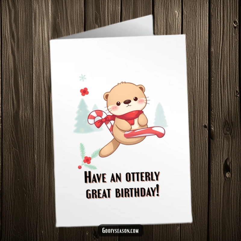 Funny Free Printable Birthday Card: Kawaii otter gleefully floating on a giant candy cane amidst snowflakes, celebrating winter merriment.