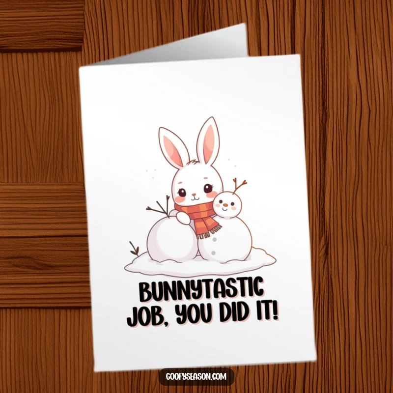 Funny Free Printable Congratulations Card: A curious bunny wearing a scarf is engrossed in building a snowman with a carrot nose.