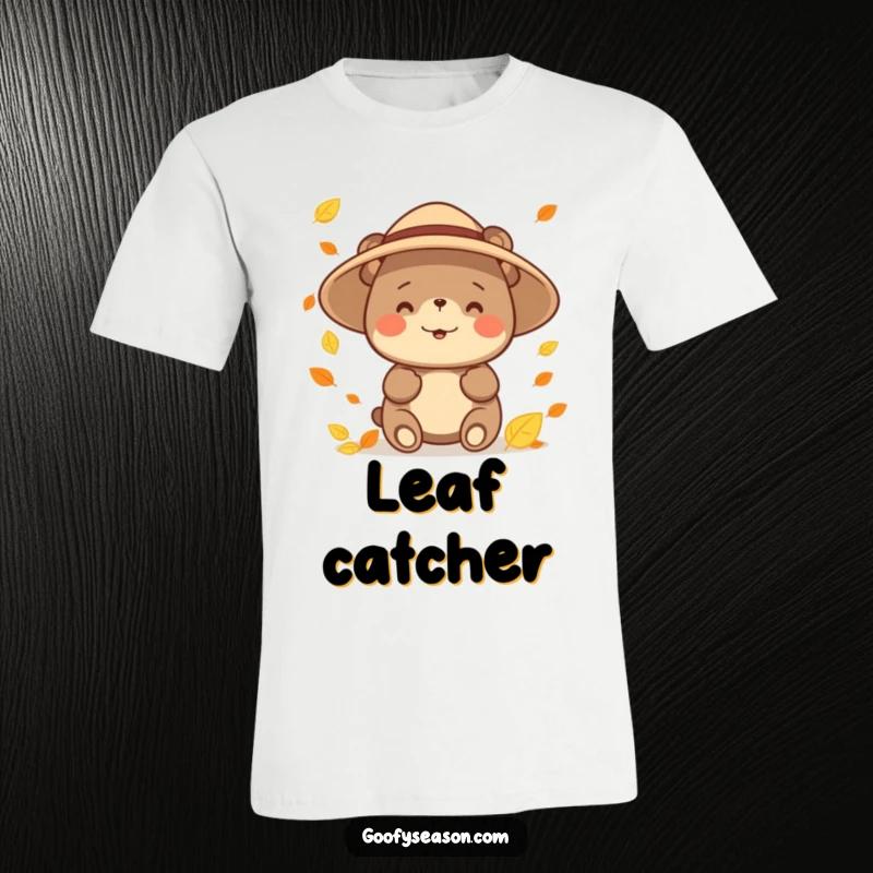 Funny happy bear character wearing a sun hat, enthusiastically catching falling autumn leaves on a T-shirt, symbolizing seasonal fun.