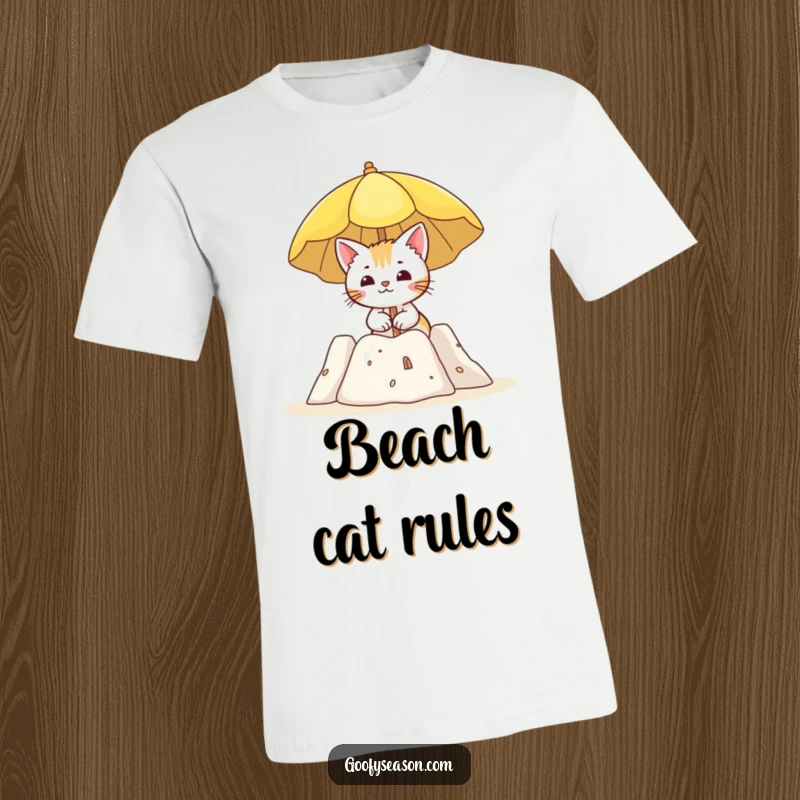 Funny t-shirt showing a curious cat holding a sun umbrella beside a sandcastle, enjoying a day at the beach.