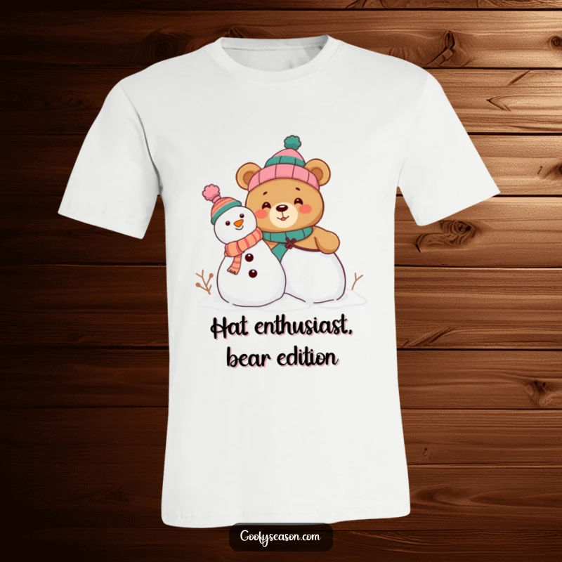 Funny t-shirt of a curious bear character excitedly building a snowman, donning various comical hats, celebrating winter with laughter.