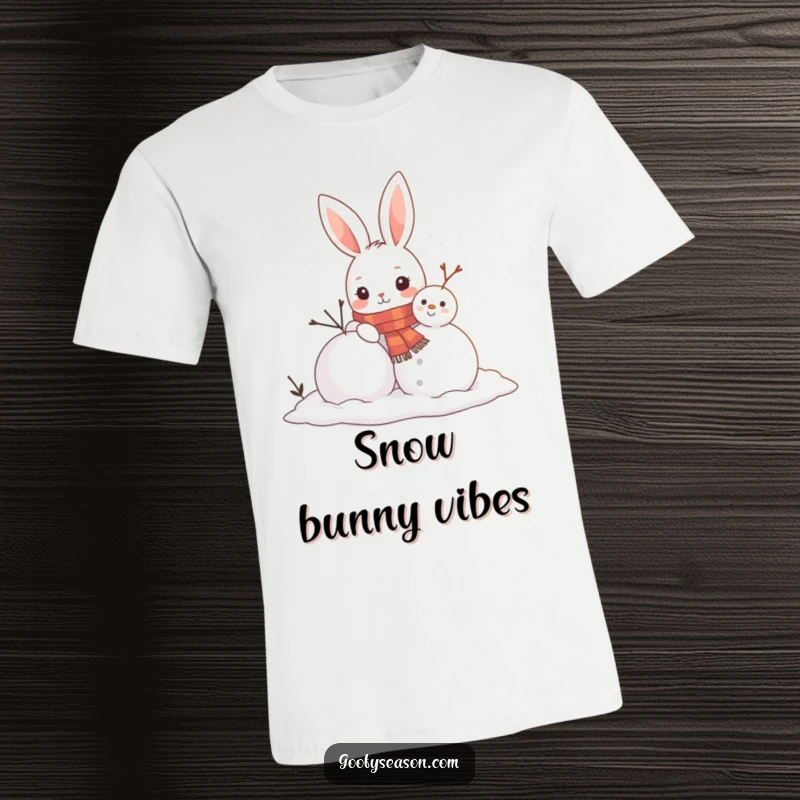 Funny t-shirt print of a curious bunny in a scarf enthusiastically building a snowman, conveying winter fun and warmth on soft fabric.