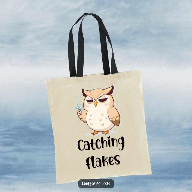 Funny tote bag with a determined owl character actively trying to catch a falling snowflake with an open beak, printed on a durable canvas.